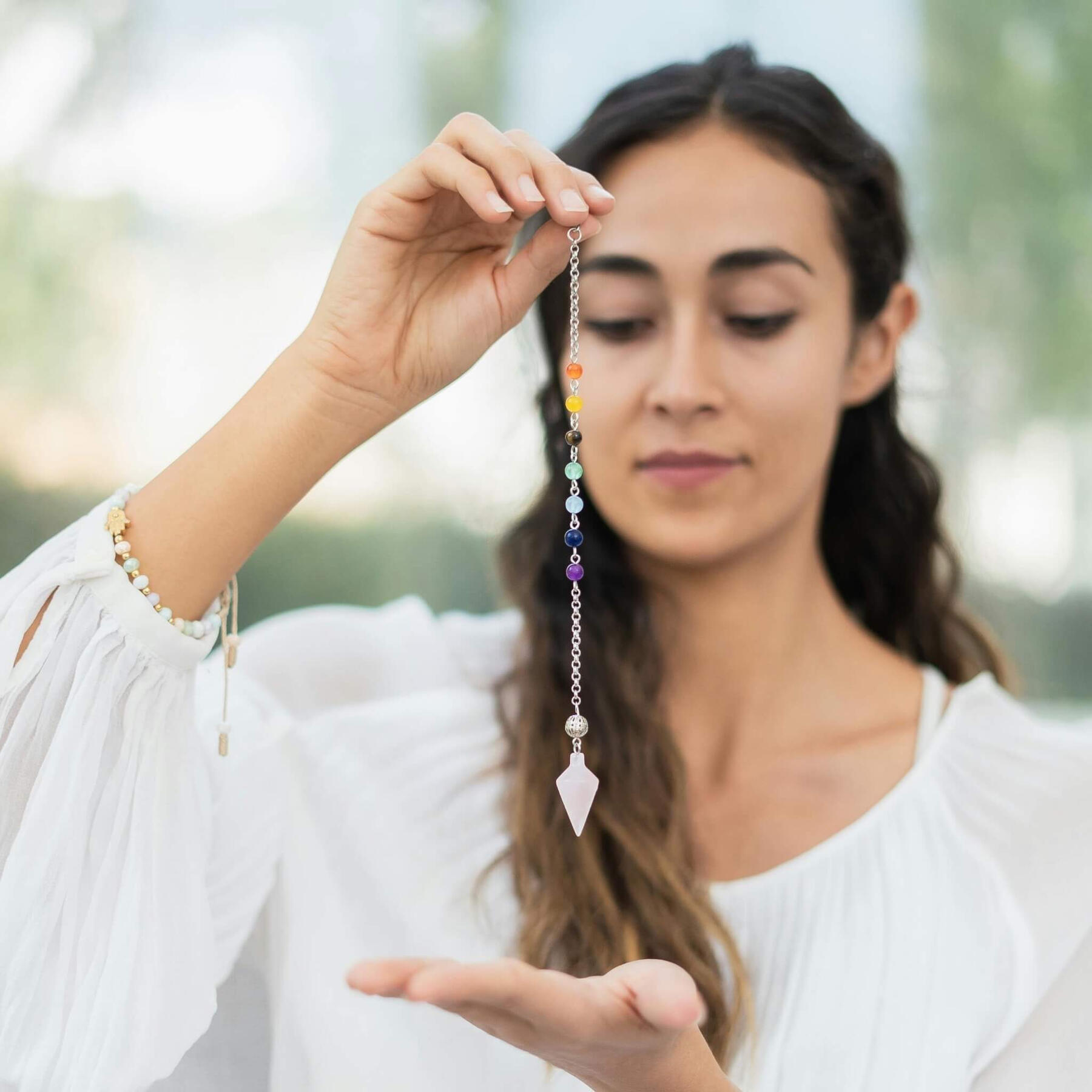 This is a photo of a lady holding a crystal pendulum